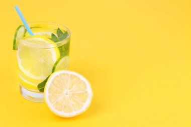Limon ve salatalık ve nane bir cam bardak taze limon parlak sarı Kağıt arka plan üzerinde yanındaki serinletici su
