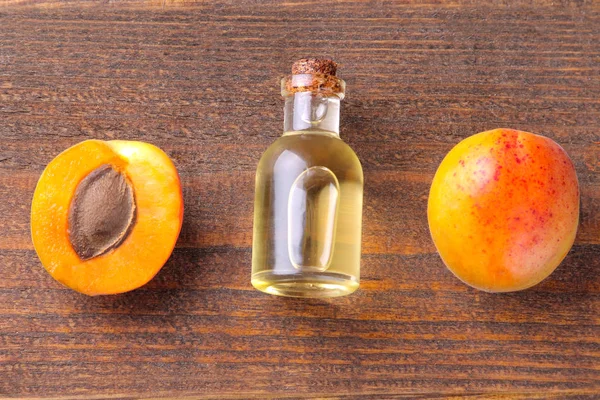 Yanında kahverengi ahşap arka plan üzerinde taze kayısı kayısı çekirdeği yağı. Üstten görünüm
