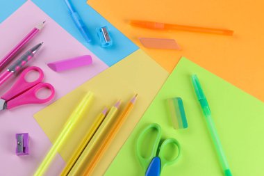 Makas kurşun kalem ve silgi parlak çok renkli arka plan üzerinde de dahil olmak üzere birçok çok renkli okul malzemeleri