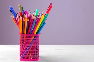 Birçok çok renkli kalemler ve gri arka plan üzerinde kalemler için bir bardak işaretleri