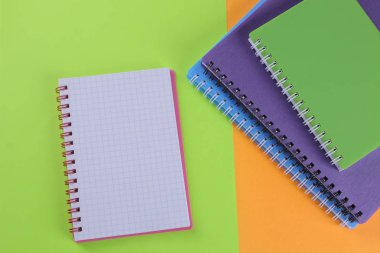 Çok çok renkli Notebook ve parlak renkli arka plan üzerinde bir not defteri. okul malzemeleri. Üstten görünüm