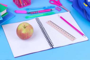 Bir defter ve kalem parlak mavi bir arka plan üzerinde ön planda ile birçok çok renkli okul malzemeleri