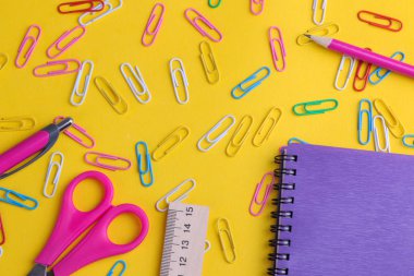 Birçok çok renkli klipleri ve okul malzemeleri parlak sarı bir arka plan üzerinde. Üstten görünüm
