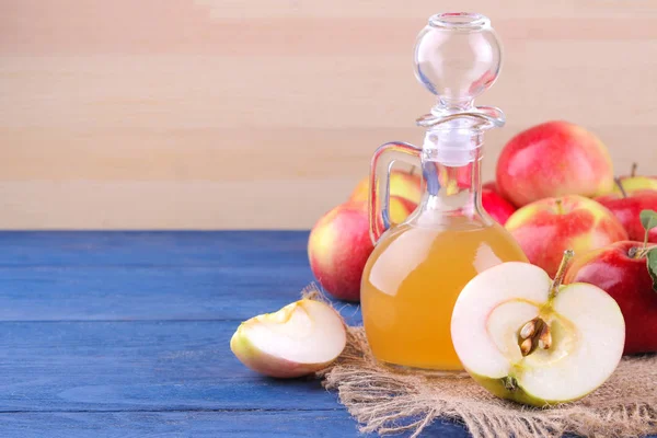 Apple vinegar with fresh ripe apples on a blue wooden background with a place for writing