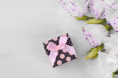 Pembe fiyonk ve güzel beyaz eustoma çiçek beyaz ahşap arka plan üstten görünüm üzerinde siyah hediye kutusu