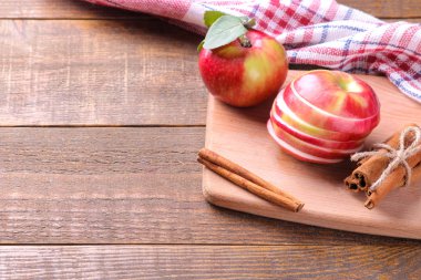Taze Olgun kırmızı elma tarçın ile kesme tahtası üzerinde sopa üzerinde kahverengi ahşap bir masa