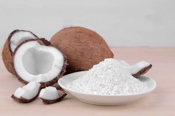 large fresh coconut and pieces of coconut on a natural wooden background
