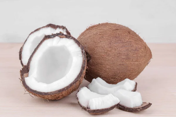 large fresh coconut and pieces of coconut on a natural wooden background