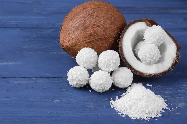 Coconut and half coconut with coconut candies on a blue wooden background