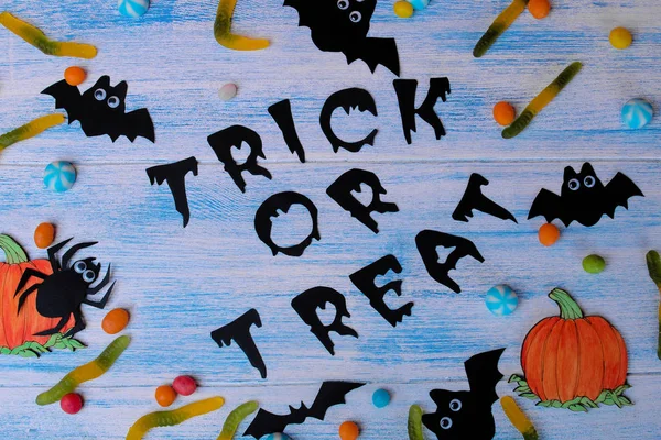 The concept of the holiday of Halloween. bats and sweets on a blue background with an inscription trick or treat top view