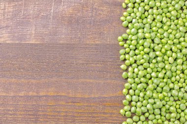 abartı yazıt için bir yer ile kahverengi ahşap bir masa bir çerçeve ile kaplı yeşil taze bezelye. üstten görünüm