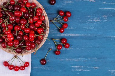 Bir buhurdan yazıt için bir mavi ahşap masada bir sepet içinde olgun kiraz ile kompozisyon. üstten görünüm