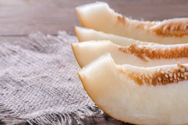 Kahverengi ahşap bir masa üzerinde beyaz bir tabak taze olgunlaşmış kavun parçaları