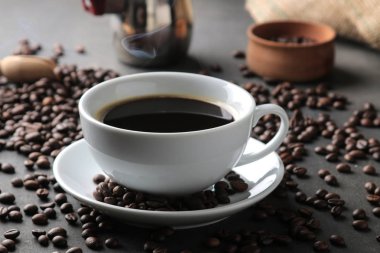 Yakın çekim ve kavrulmuş kahve çekirdeği etrafında siyah bir zemin üzerine fincan kahve bir beyaz.