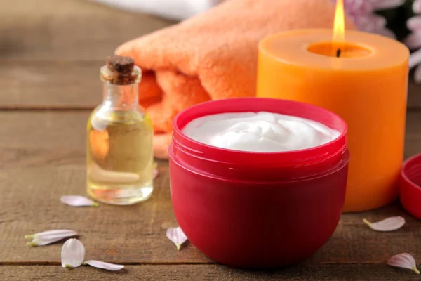 Cosmetic cream in a red jar of candle oil towel in the background on a brown wooden table. spa. relax. cosmetics