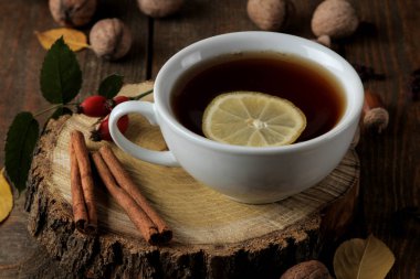 Bir ahşap stand, tarçın, köpek rose, kahverengi ahşap bir masa fındık sıcak çay ile sonbahar kompozisyon