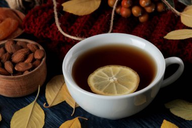 Sıcak çay fındık ile sonbahar kompozisyon çilek ve koyu mavi ahşap bir masa üzerinde sarı sonbahar yaprakları