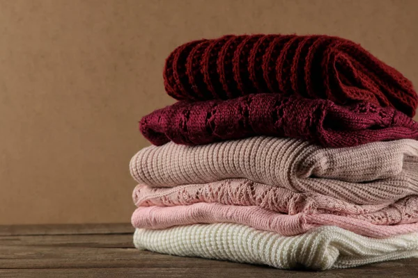 Bir kahverengi ahşap arka plan üzerinde Kazıklı çeşitli sıcak kazak ile sonbahar kompozisyon