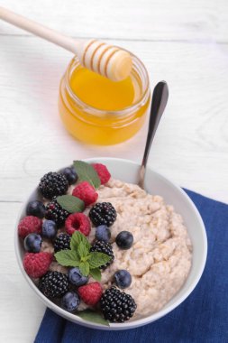 Çilek ve bal beyaz ahşap bir masa üzerinde bir kase yulaf ezmesi. Kahvaltı. sağlıklı gıda.