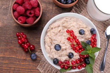 Çilek ve kahverengi ahşap bir masa üzerinde bir kasede süt yulaf ezmesi. Kahvaltı. sağlıklı gıda. üstten görünüm