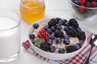 Çilek ve bal beyaz ahşap bir masa üzerinde bir kase yulaf ezmesi. Kahvaltı. sağlıklı gıda.