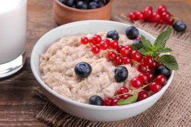 Çilek ve kahverengi ahşap bir masa üzerinde bir kasede süt yulaf ezmesi. Kahvaltı. sağlıklı gıda.