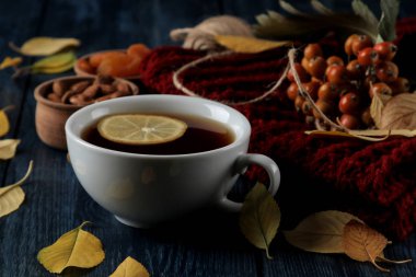 Sıcak çay fındık ile sonbahar kompozisyon çilek ve koyu mavi ahşap bir masa üzerinde sarı sonbahar yaprakları