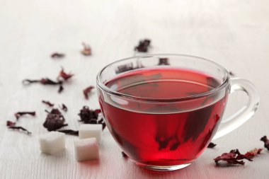 Beyaz ahşap bir masa üzerinde kuru çay ile cam bardak sıcak kırmızı pembe çay