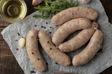 Roka, tereyağı ve sarımsak yemek pişirmek için malzemelerle çiğ sosis. kahverengi ahşap bir masa üzerinde. üstten görünüm