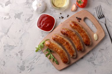 Sebze domates ve sarımsak, kırmızı sos ve baharat hafif bir arka plan üzerinde çeşitli ızgara sosis. üstten görünüm