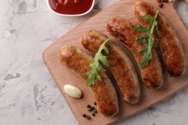 Sebze domates ve sarımsak, kırmızı sos ve baharat hafif bir arka plan üzerinde çeşitli ızgara sosis. üstten görünüm