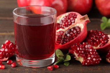 Üzerinde kahverengi ahşap bir masa taze nar ile bir bardak nar suyu