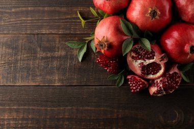 Olgun nar meyve kahverengi ahşap zemin üzerine yeşil yaprakları ile bileşimi. yazıt yeri olan üstten görünüm