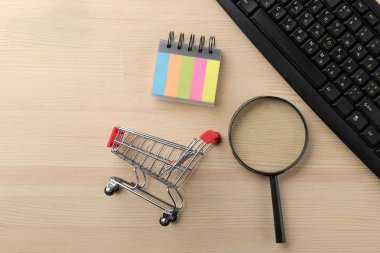 Online alışveriş kavramı. Bir büyüteç ve tablonun arka plan üzerinde bir alışveriş arabası ile kompozisyon