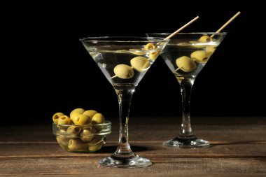 Cam bardağı kahverengi ahşap bir masa üzerinde bir şiş üzerinde yeşil zeytinli martini. kokteyller. Bar