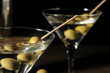 Cam bardağı kahverengi ahşap bir masa üzerinde bir şiş üzerinde yeşil zeytinli martini. kokteyller. Bar