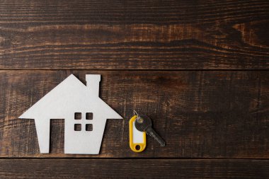 Bir ev satın alma kavramı. Dekoratif hut ve ev anahtarları bir yer bir yazıt için bir kahverengi ahşap zemin üzerine. üstten görünüm