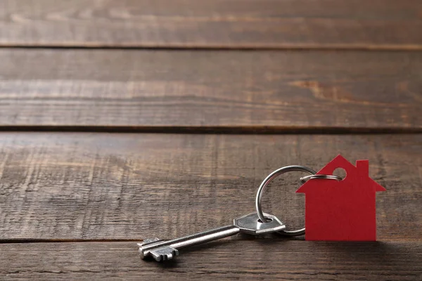 买房的概念 钥匙与钥匙串房子在棕色木制背景 有刻字空间 — 图库照片