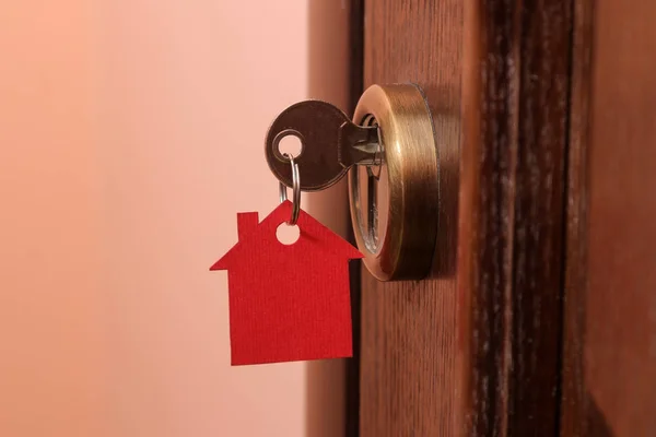 The concept of buying a home. Keys with keychain house in the door lock close-up