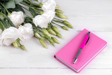 Yanındaki beyaz ahşap zemin üzerinde eustoma çiçek pembe kadın Not defteri