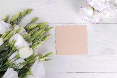 Güzel beyaz çiçekler. Eustoma. Beyaz ahşap bir masa üzerinde bir yazıt biçimle