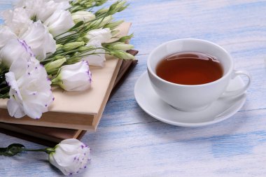 Güzel beyaz çiçekler. Mavi ahşap bir masa üzerinde kitapların bir yığınına Eustoma buket.