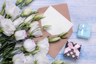 Güzel beyaz çiçekler. Eustoma buket hediye, bir zarf ile boş bir metin üzerinde mavi bir ahşap masa için. yukarıdan görüntülemek