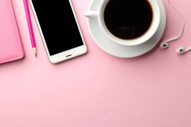Beyaz akıllı telefon ve kulaklık ve parlak pembe bir arka plan üstünde not etmek. yukarıdan görüntülemek