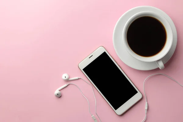 Kulaklıklar ve bir fincan kahve parlak pembe bir arka plan üzerinde beyaz smartphone. yukarıdan görüntülemek