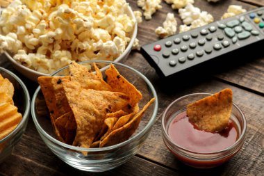 Tortilla ve patlamış mısır, Tv bir kahverengi ahşap arka plan üzerinde uzak. evde film izlerken kavramı. yakın çekim.