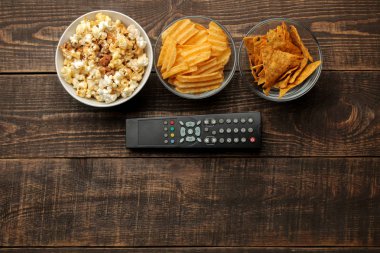 Tortilla patlamış mısır, cips ve Tv bir kahverengi ahşap arka plan üzerinde uzak. evde film izlerken kavramı. yukarıdan görüntülemek