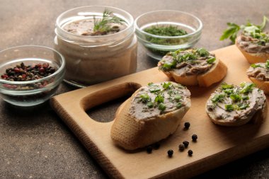 Taze ev yapımı tavuk karaciğer pate ekmek üzerinde karanlık bir arka plan üzerinde yeşillikleri ile. Bir sandviç.