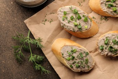 Taze ev yapımı tavuk karaciğer pate ekmek üzerinde karanlık bir arka plan üzerinde yeşillikleri ile. yukarıdan görüntülemek