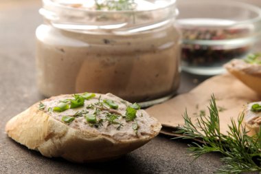 Taze ev yapımı tavuk karaciğer pate ekmek üzerinde karanlık bir arka plan üzerinde yeşillikleri ile. Bir sandviç. yakın çekim